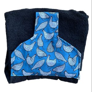 Hand towel to go over a rail. Fastened with a magnetic popper. Towel black. Towel top mid blue with white cartoon like hens.